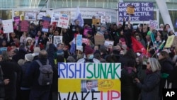 Perawat memegang spanduk dan plakat saat berlangsungnya aksi mogok di luar Royal College of Nursing, London, Rabu, 18 Januari 2023. (AP/Kin Cheung)