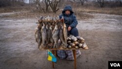 Serhi Zamulenko sells fish on the side of the road, despite shells frequently falling in the area, in Chasiv Yar, Ukraine, Jan. 22, 2023. (Yan Boechat/VOA)