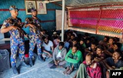 FILE - Detained Rohingya refugees sit next to security personal after crackdown in Rohingya refugee camp in Ukhia, Oct. 28, 2022. (AFP photo / Bangladesh Armed Police Battalion)
