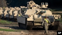 FILE - A U.S. walks near Abrams battle tanks near Vilnius, Lithuania, on Oct. 21, 2019.