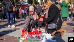 Dos mujeres encienden velas en memoria de un sacristán asesinado el miércoles en Algeciras, en el sur de España, el jueves 26 de enero de 2023.