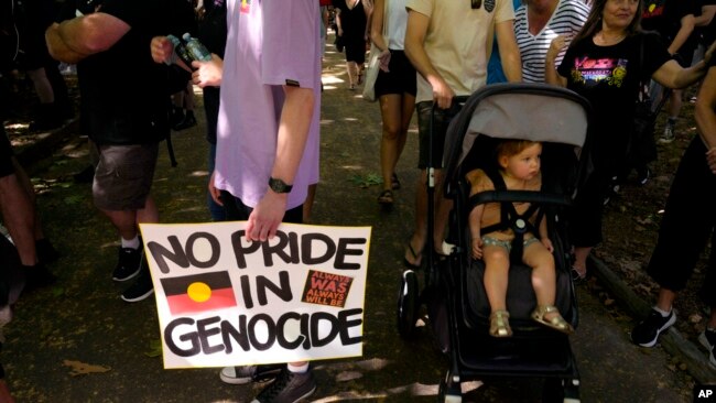 A man carries a placard at an Invasion Day rally in Sydney, Jan. 26, 2023.