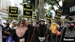 Perempuan Muslim Indonesia membawa plakat dalam aksi protes atas pembakaran Al-Qur'an di Swedia, di luar Kedutaan Besar Swedia di Jakarta, 30 Januari 2023. (REUTERS/Willy Kurniawan)
