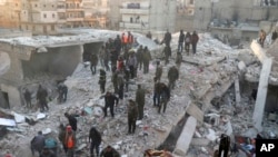 In this photo provided by Kurdish-run Hawar News Agency, civil defense workers and civilians work on the rubble of a destroyed building in the Sheikh Maksoud neighborhood in Aleppo, Syria, Jan. 22, 2023. 