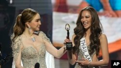 FILE - Anne Jakkaphong Jakrajutatip presents the ImpactWayv Challenge Award to Miss Thailand Anna Sueangam-iam during the final round of the 71st Miss Universe Beauty Pageant in New Orleans, Jan. 14, 2023.