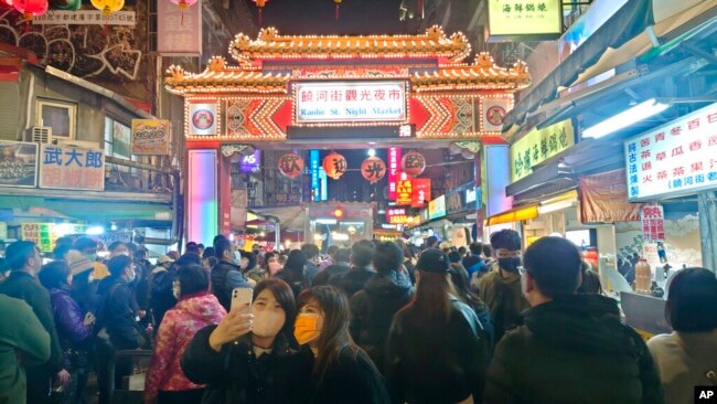 People wear face masks to protect against the spread of the coronavirus at a night market during the Lunar New Year celebrations in Taipei, Jan. 25, 2023.