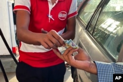 FILE - A driver hands over Myanmar kyats to an attendant as payment for fuel at a gas station in Botahtaung township in Yangon, Myanmar, Nov. 12, 2021.