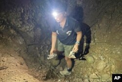 In this photo provided by the Free Burma Rangers, a man holds bomb shrapnel in a crater at a church in Lay Wah, one of the villages in Karen state’s Mutraw district, Myanmar, Jan. 12, 2023.