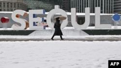 韩国首尔一名女子走过降雪的城市街头。（2023年1月26日）