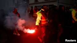 Protesters hold flares during a demonstration against French government's pension reform plan in Saint-Nazaire as part of a day of national strike and protests in France, Jan. 19, 2023.