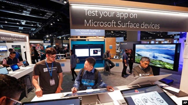 FILE - Workers demonstrate Microsoft Surface devices at the Microsoft Build 2017 developers conference, May 10, 2017, in Seattle.