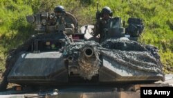 Dua tentara AS di atas tank M1 Abrams melakukan pergerakan kendaraan sebagai bagian dari pelatihan bagi pasukan Ukraina di Area Pelatihan Hohenfels, Jerman, 2 Juni 2022.