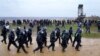 Polisi berjalan di dekat para pengunjuk rasa di tambang Garzweiler dekat desa Luetzerath, Erkelenz, Jerman, Sabtu, 14 Januari 2023. (AP/Michael Probst)