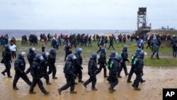 Polisi berjalan di dekat para pengunjuk rasa di tambang Garzweiler dekat desa Luetzerath, Erkelenz, Jerman, Sabtu, 14 Januari 2023. (AP/Michael Probst)