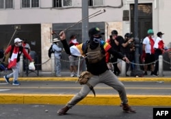 Demonstran mengayunkan ketapel saat bentrok dengan polisi anti huru hara dalam protes terhadap pemerintah Dina Boluarte. (Foto: AFP)