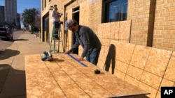 Ryan Kellum, center, and Ricky Noe install plywood over windows at Caliber Collision, Jan. 27, 2023, in Memphis, Tenn. Kellum said the company he works for was protecting windows ahead of the release of the video of Tyre Nichols' arrest.