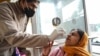 A health worker collects a nasal swab sample from a woman to test for COVID-19 at a hospital in Amritsar on Jan. 5, 2023.