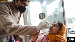 A health worker collects a nasal swab sample from a woman to test for COVID-19 at a hospital in Amritsar on Jan. 5, 2023.