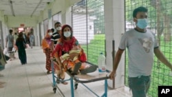 বাংলাদেশের রাজধানী ঢাকা থেকে ২৫৪ কিলোমিটার (১৫৮ মাইল) উত্তরে রাজশাহী মেডিকেল কলেজ হাসপাতালে একজন করোনা আক্রান্ত রোগীকে স্ট্রেচারে করে নিয়ে যাওয়া হচ্ছে। ১৬ জুন, ২০২১। (ফাইল ছবি) 