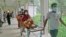 বাংলাদেশের রাজধানী ঢাকা থেকে ২৫৪ কিলোমিটার (১৫৮ মাইল) উত্তরে রাজশাহী মেডিকেল কলেজ হাসপাতালে একজন করোনা আক্রান্ত রোগীকে স্ট্রেচারে করে নিয়ে যাওয়া হচ্ছে। ১৬ জুন, ২০২১। (ফাইল ছবি) 