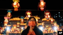 Seorang perempuan mengenakan masker saat berdoa di Kuil Wong Tai Sin, di Hong Kong, pada 21 Januari 2023, sebagai bagian dari perayaan Tahun Baru Imlek. (Foto: AP/Bertha Wang)