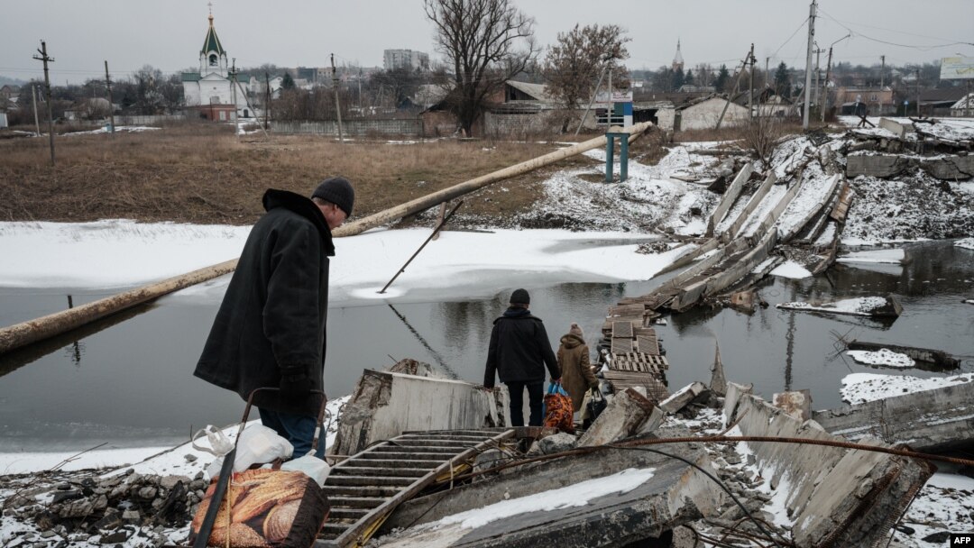 La gente camina sobre un puente destruido para cruzar un canal hacia el área en disputa en Bakhmut el 1 de febrero de 2023, en medio de la invasión rusa de Ucrania. (Foto de YASUYOSHI CHIBA / AFP)