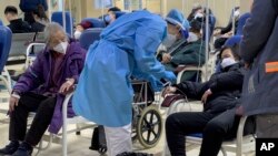 An elderly patient watches a medical worker check on a woman as they receive intravenous drips in an emergency ward in Beijing, Jan. 19, 2023.