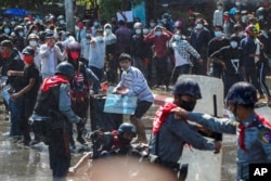 FILE - Protesters run after police shot warning shots and used water cannon to disperse them during a protest in Mandalay, Myanmar, on Feb. 9, 2021.