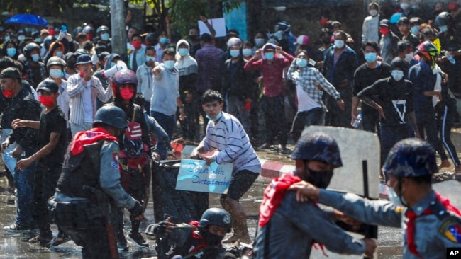 FILE - Protesters run after police shot warning shots and used water cannon to disperse them during a protest in Mandalay, Myanmar, on Feb. 9, 2021.