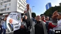 FILE - Tunisian supporters carry a portrait of President Kais Saied as they take to the streets to support him during protests by the opposition in Tunis, Tunisia, Jan. 14, 2023.