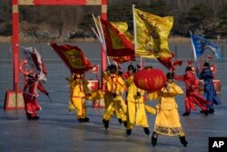 Seniman China mengenakan kostum tradisional, melakukan pertunjukan di danau beku di Taman Yuanmingyuan pada hari kedua perayaan Tahun Baru Imlek di Beijing, Senin, 23 Januari 2023. (AP/Andy Wong)