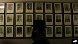 Un judío ortodoxo pasa frente a los retratos de las víctimas en el antiguo campo de concentración y exterminio nazi alemán Auschwitz-Birkenau en Oswiecim, Polonia, el jueves 26 de enero de 2023.