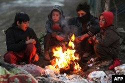 Sejumlah laki-laki Afghanistan duduk di dekat api unggun di sepanjang jalan, pada musim dingin di Kabul pada 30 Desember 2022. (Foto: AFP)