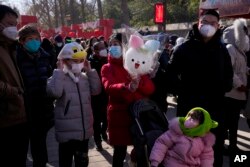 Seorang perempuan memegang permen kapas berbentuk kelinci saat dia dan anggota keluarganya mengunjungi pekan raya di Taman Yuanmingyuan pada hari kedua perayaan Tahun Baru Imlek di Beijing, Senin, 23 Januari 2023. (AP/Andy Wong)