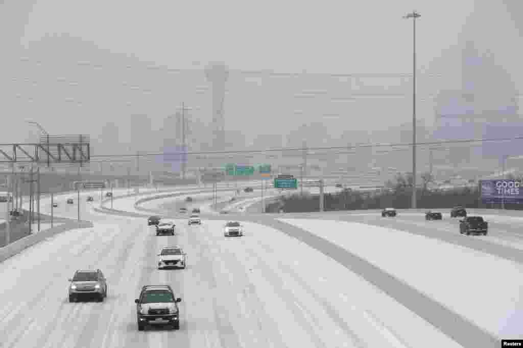 Cars drive down an icy highway as cold weather moves through Dallas, Texas.