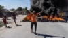 A man gestures by a barricade of flaming tires during a police demonstration in Port-au-Prince, Haiti, Jan. 26, 2023. Officers were protesting after a gang attack the day before on a police station in Liancourt left several officers dead.