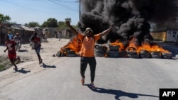 A man gestures by a barricade of flaming tires during a police demonstration in Port-au-Prince, Haiti, Jan. 26, 2023. Officers were protesting after a gang attack the day before on a police station in Liancourt left several officers dead.