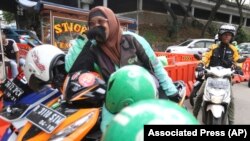 Seorang perempuan pengemudi transportasi online menunggu pelanggan di Jakarta, 26 Maret 20218. (Foto: Achmad Ibrahim/AP)