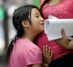 FILE - Immigrant Maricelda Mejilla, 6, hugs her pregnant mother, Meregilda, as they wait inside the central bus station after they were processed and released by U.S. Customs and Border Protection, June 24, 2018, in McAllen, Texas.