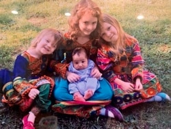 In this undated photo, U.S. Special Forces Officer Ryan Brummond’s daughters pose with an Afghan interpreter's son wearing dresses that were gifted to them by Mohammad Khalid Wardak to celebrate the collective relationship between the men