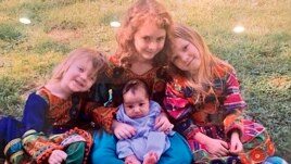 In this undated photo, U.S. Special Forces Officer Ryan Brummond’s daughters pose with an Afghan interpreter's son wearing dresses that were gifted to them by Mohammad Khalid Wardak to celebrate the collective relationship between the men
