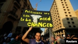 Seorang demonstran di Beirut membawa poster bertuliskan "Politisi seperti popok, harus diganti" pada sebuah protes Kamis (20/6). (Reuters/Sharif Karim)