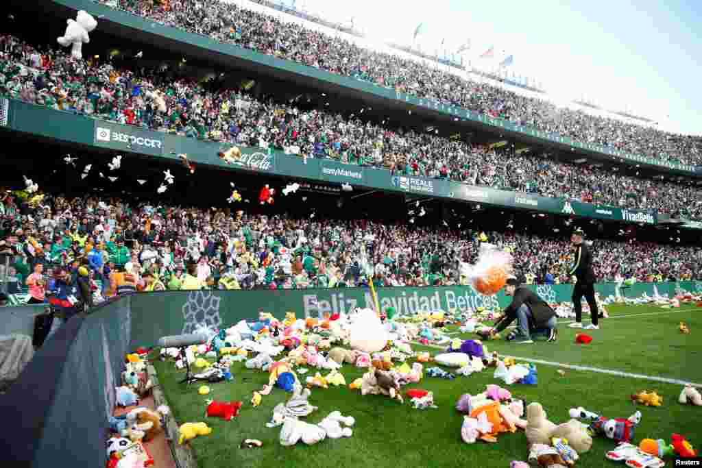 Fans throw toys to the pitch for charity during the half-time break of the Spanish league football match between Real Betis and Atlentico Madrid at the Benito Villamarin statium in Seville, Spain.