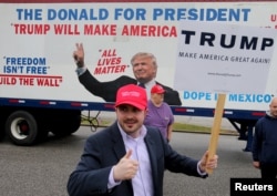 Bob Bolus, a supporter of U.S. Republican presidential candidate Donald Trump, gives the thumbs up to drivers as they pass by in Middleburg Heights, Ohio, March 15, 2016.