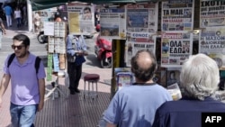 People read newspaper's headlines in central Athens on June 15, 2015. 