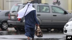 Un homme en tenue arabe du Golfe se promène sous la pluie à Dubaï, Émirats arabes unis, 9 mars 2016. (AP Photo / Kamran Jebreili)