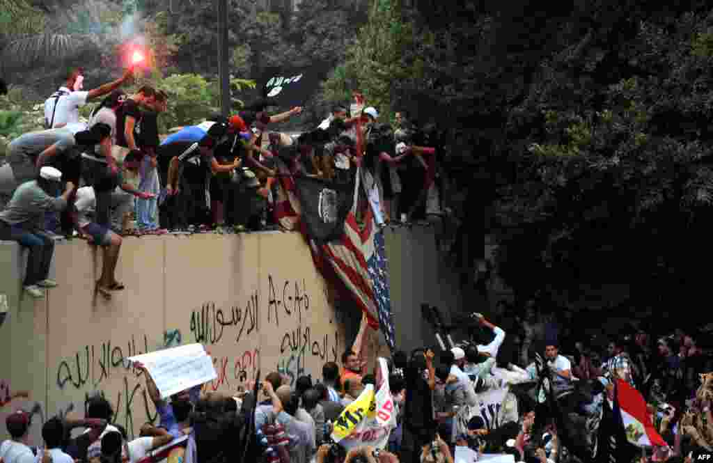 Des manifestants &eacute;gyptiens escaladant le mur de l&#39;ambassade am&eacute;rcaine en Egypte et agitant un drapeau islamiste