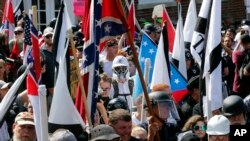 FILE - White nationalist demonstrators walk into the entrance of Lee Park surrounded by counter demonstrators in Charlottesville, Va., Aug. 12, 2017. 