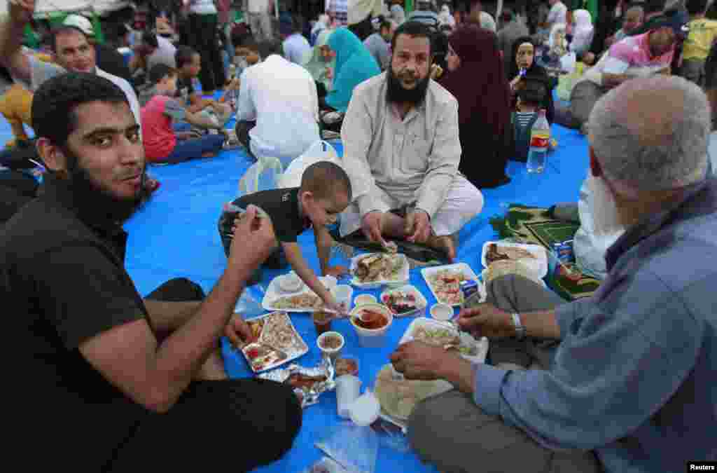 Para pendukung Mohamed Morsi yang baru dikudeta militer berbuka puasa pada hari pertama Ramadan di luar masjid Rabaa Adawiya di Kairo (10/7). (Reuters/Louafi Larbi)