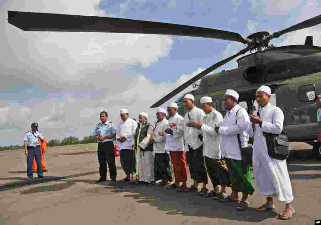 Para ulama berdoa sebelum menaiki helikopter NAS 332 Super Puma milik Angkatan Udara Indonesia. Para ulama itu akan terbang melintasi Laut Jawa tempat jatuhnya pesawat AirAsia bernomor penerbangan 8501 untuk mendoakan para korban, di Bandar Udara Iskandar di Pangkalan Bun, Kalimantan Tengah, Indonesia (6/1). (AP/Achmad Ibrahim)